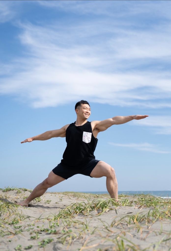 海辺でヨガウォーリアポーズをするインストラクター