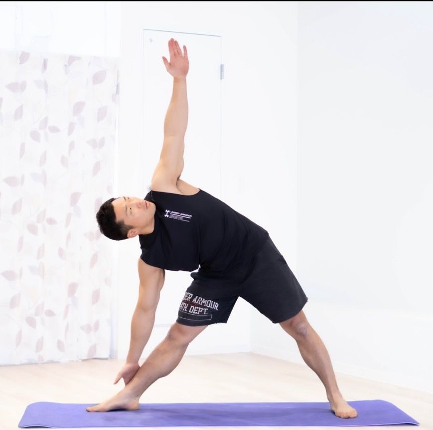 スタジオでトライアングルポーズをするインストラクター